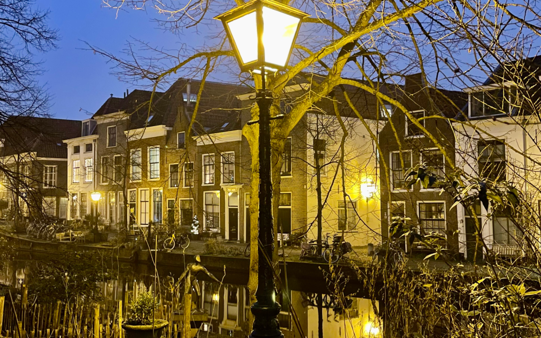 Glowing lamppost by a quiet canal at dusk, capturing a moment of stillness and presence.